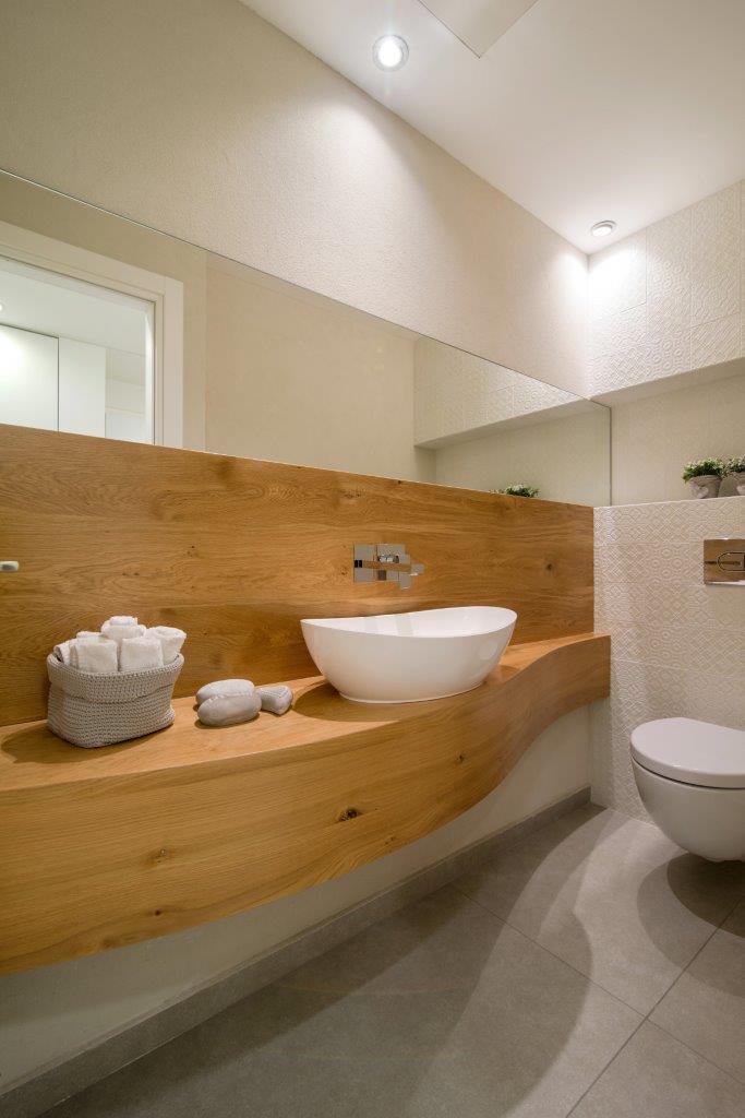 Cloakroom — an oak veneer counter cut in a wave, a countertop basin and a mirror the full width of the wall
