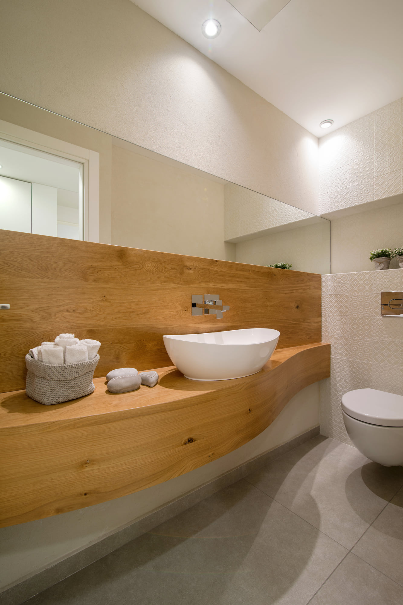 Cloakroom — an oak veneer counter cut in a wave, a countertop basin and a mirror the full width of the wall