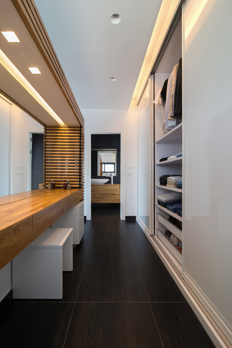 A long timber surface and open shelves with towels, in concealed light