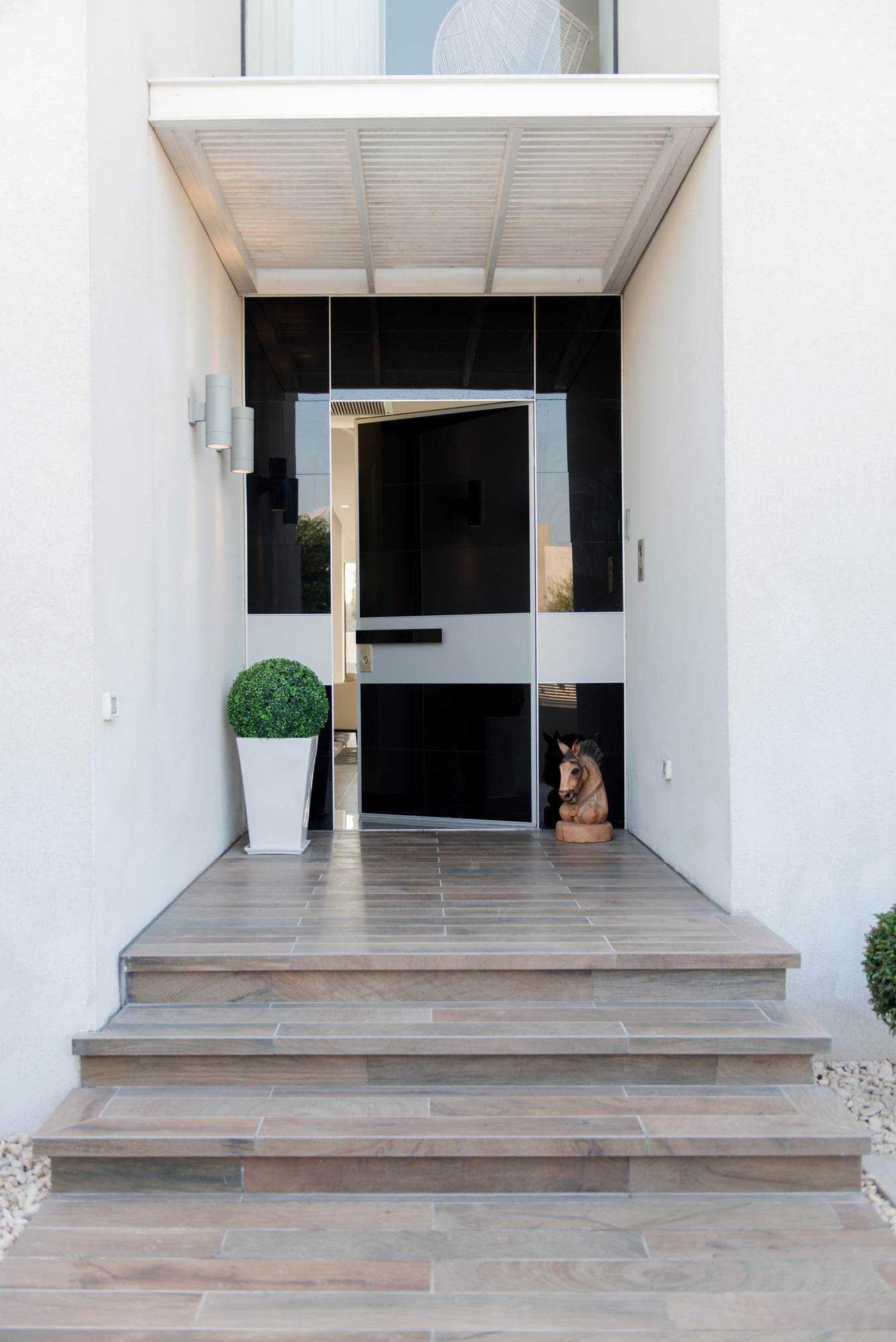 The entrance — steps up to a black door beneath a shaded roof