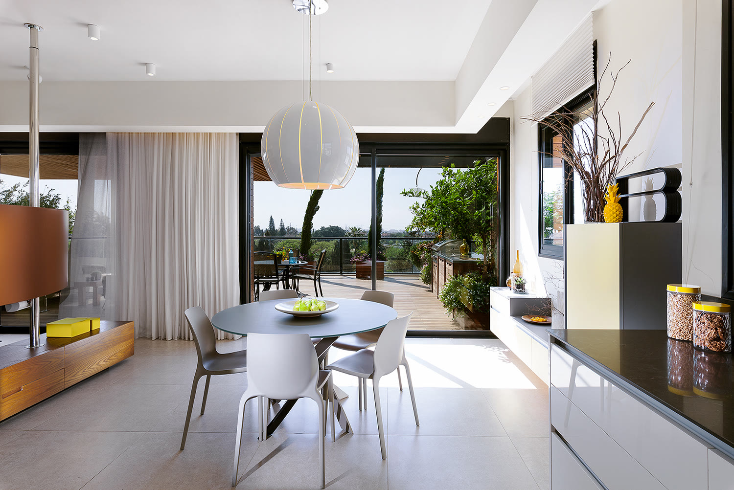 פינת האוכל — השולחן העגול כ"כיכר" שסביבה זורמים מהמטבח אל המרפסת, תחת מנורת תלייה גדולה